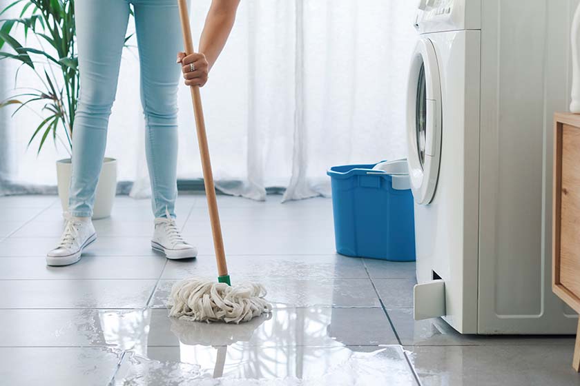 Women mopping water off floor after washing machine flood